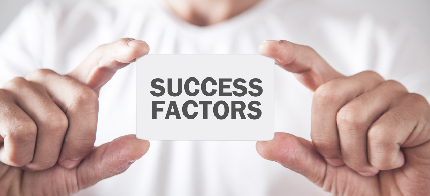 Foto di persona che tiene in mano un cartoncino con scritto Success Factors