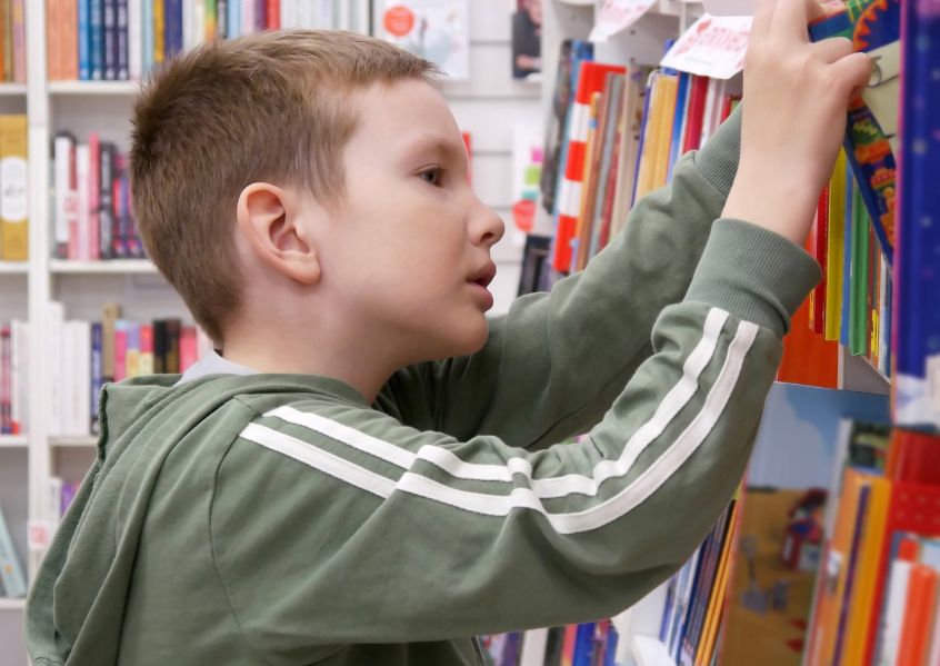 Foto di bambino che sceglie un libro in libreria